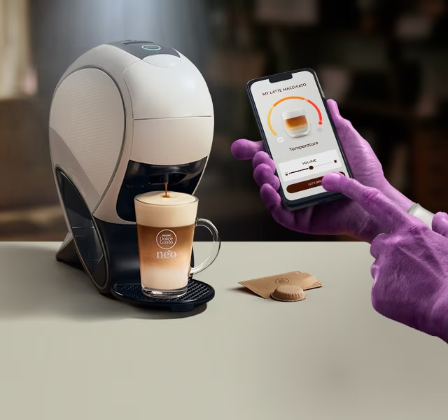 Eine Alien-Hand nutzt die NESCAFÉ® Dolce Gusto® App, um einen Kaffee zu personalisieren. NEO Latte Kaffeemaschine, Kaffee-Pack und Getränke.