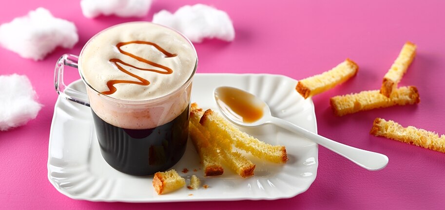 Grande im Glas Milch-Toffee-Mousse daneben Brioche-Streifen